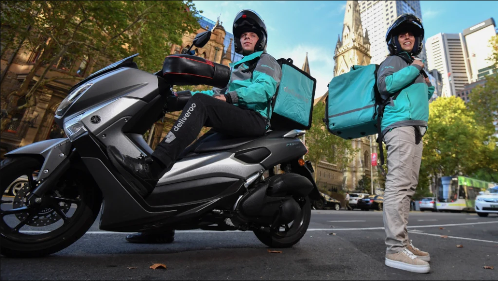 Professional Deliveroo delivery drivers with motorcycle in London street